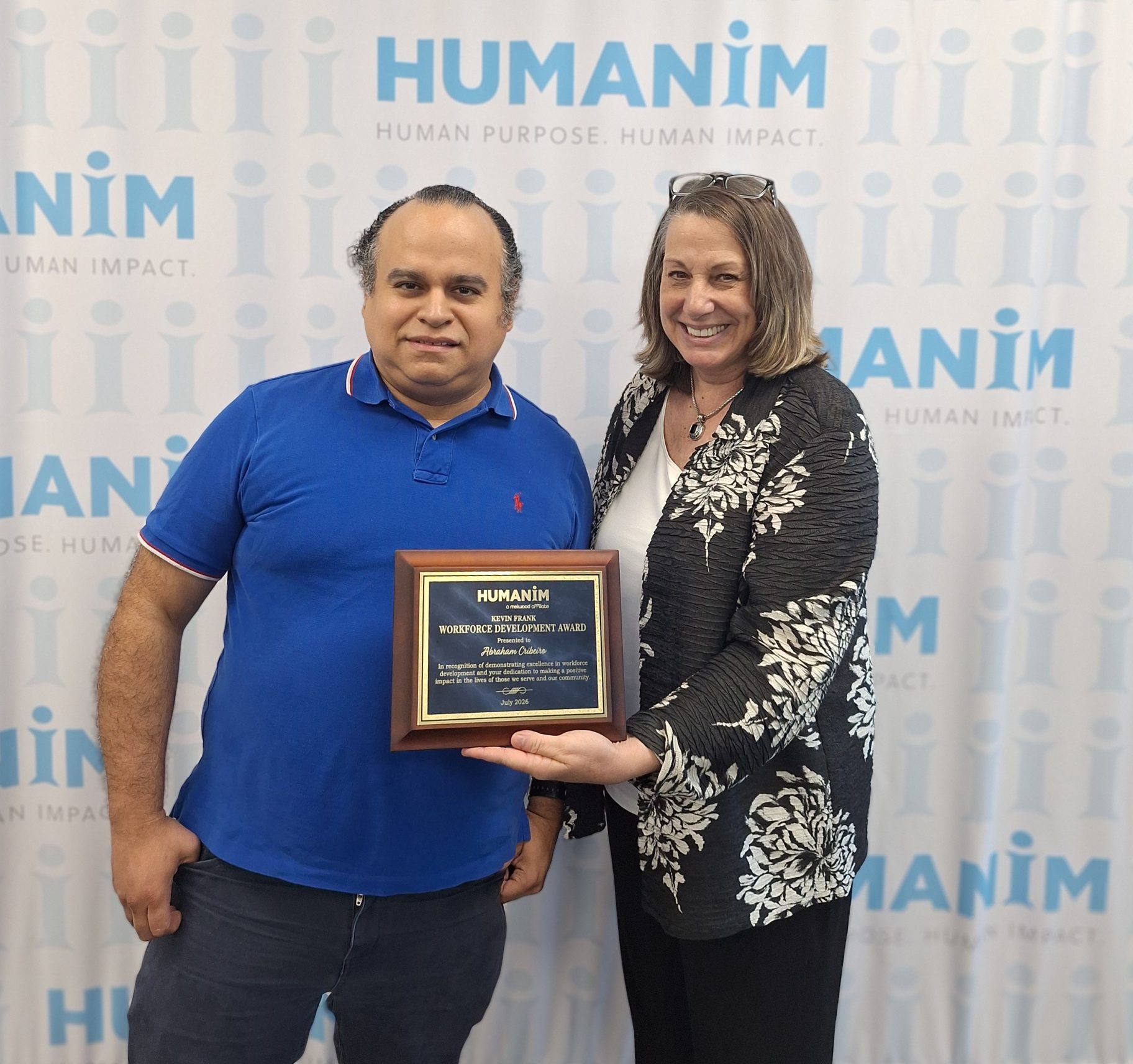 Abe standing next to Cindy Truitt, Humanim President. Smiling and holding up a plaque.