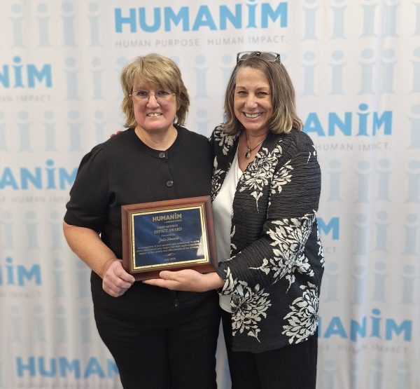Julie smiling and standing next to Cindy Truitt, Humanim president. Cindy is holding Julie's plaque, the Chris Eddings Impact award.