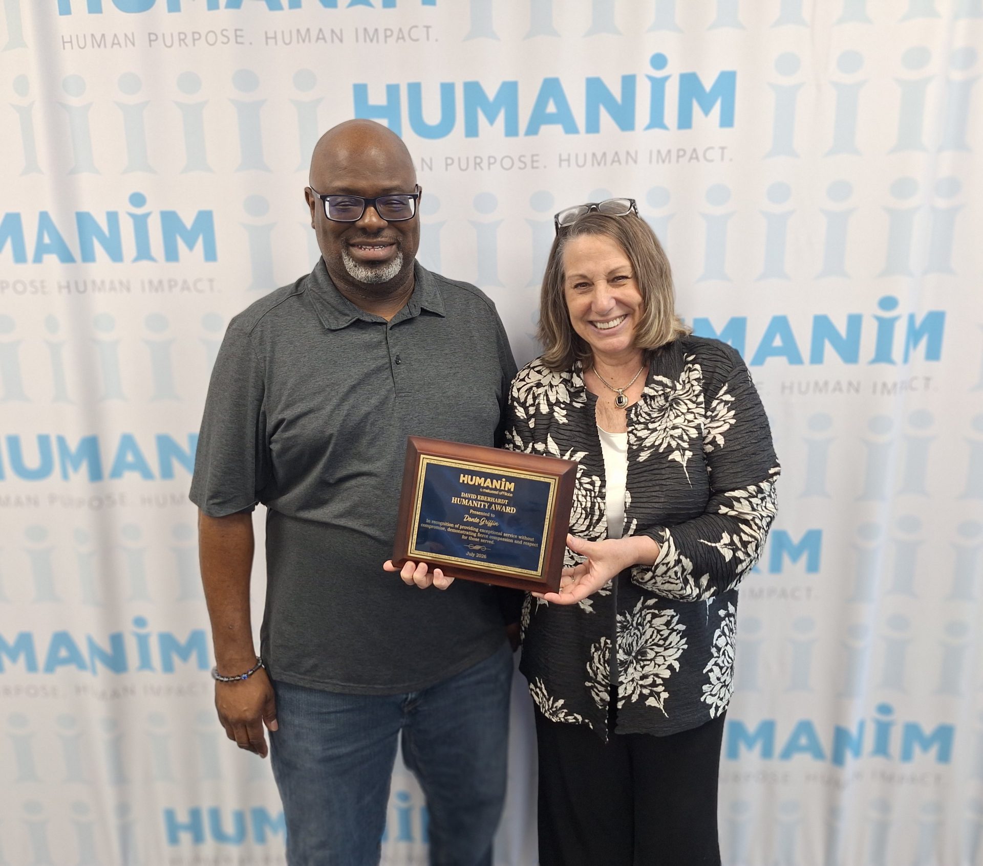 Donte standing next to Humanim President, Cindy Truitt, smiling while holding the David Eberhardt Humanity Award.